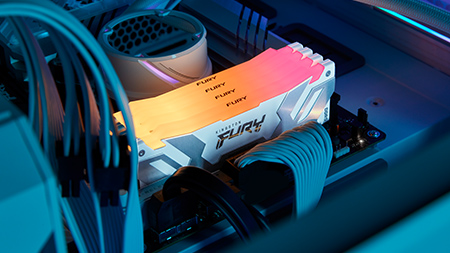 Módulos DDR5 RGB Kingston FURY Renegade instalados em um gabinete branco, emitindo um gradiente de luz amarela para vermelha.