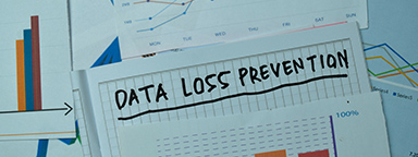 Слова "Data Loss Prevention" (Предотвращение потери данных), написанные на заметках с графиками и диаграммами на офисном столе.