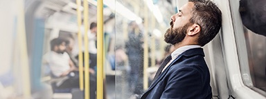 Uomo d'affari addormentato che si reca al lavoro in un treno della metropolitana di Londra