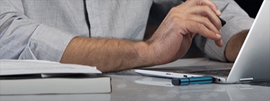 Tampilan jarak dekat pada laptop dengan drive USB Kingston IronKey yang terpasang dan tangan seorang pria yang sedang mengetik di keyboard