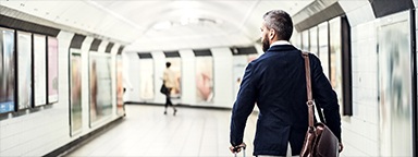 Rückenansicht eines Geschäftsmannes mit Tasche und Koffer in der Londoner U-Bahn