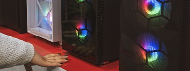 Pre-built gaming PC cases on display in a store with a girl’s hand visible in the foreground