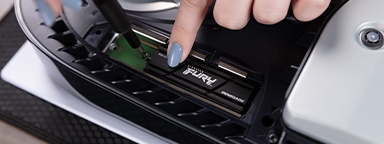 Un primer plano de las manos instalando Kingston FURY Renegade con un disipador de calor en una ranura de expansión para consola PS5