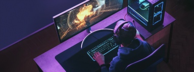 Pandangan atas seorang gamer mengenakan headphone sedang bermain game video tembak-menembak