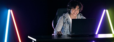 молодой геймер играет на своем ноутбуке в темной комнате