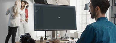 스튜디오에서 모니터에 Photoshop 로딩 화면이 떠있는 데스크톱 컴퓨터로 작업하고 있는 사진 편집자