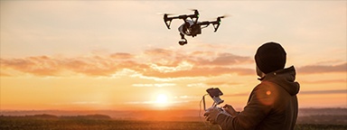Immagine di un uomo che controlla un drone con un radiocomando al tramonto