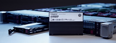 Два твердотельных накопителя Kingston DC3000ME, один вертикально стоящий, другой — лежит перед серверной стойкой на столе