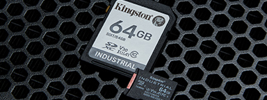 A pair of Kingston 64GB Industrial microSD cards siting on a distressed metal surface