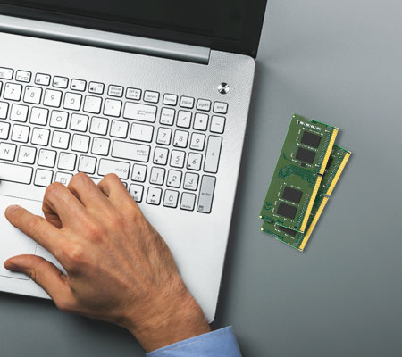 Zwei RAM-Module neben der Hand einer Person auf einem Laptop