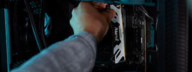Seseorang memasukkan modul memori Kingston FURY Renegade DDR5 ke casing komputer berwarna hitam.