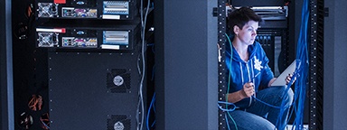 Un tecnico di rete donna vicino a un server rack con un cavo ethernet
