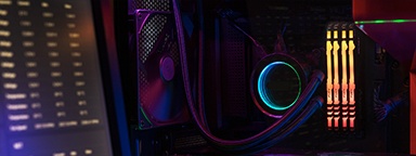 Kingston FURY Beast RGB con un ventilador de enfriamiento de CPU y cables conectados a una placa madre con un monitor a la izquierda mostrando las especificaciones de la PC