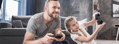 Pai e filha sentados no tapete de casa jogando videogame