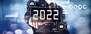 A businessman pointing at an illustration of business icons and graphs with 2022 in the middle