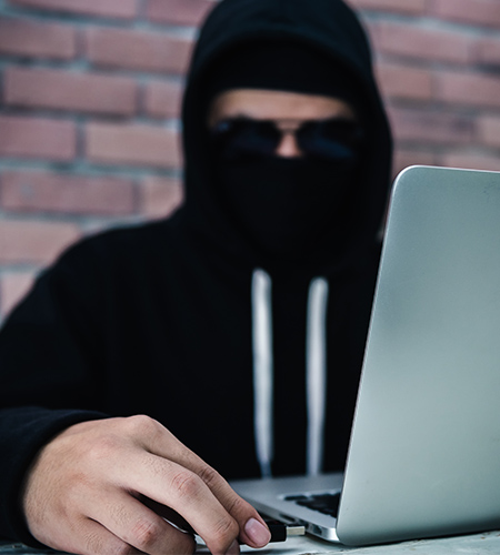 Immagine di un hacker incappucciato che opera su un laptop