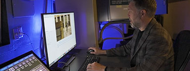 數位電影放映師 Ryan Carpenter 坐在電腦螢幕前。