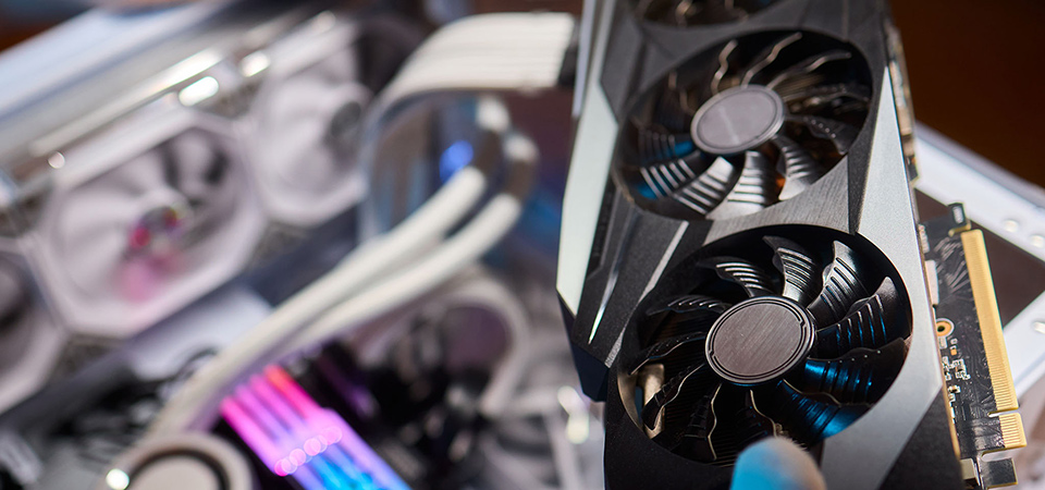 Unas manos con guantes de goma sostienen ventiladores para instalar en un PC con m&oacute;dulos de memoria RGB.