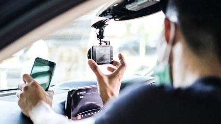 Ein Fahrer stellt seine Dashcam ein, während er sein Telefon hält.