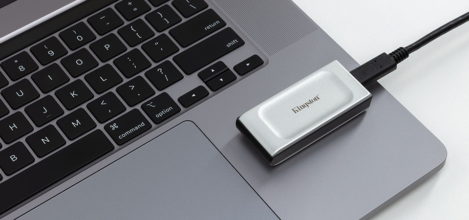 Um SSD externo Kingston XS2000 conectado a um laptop.