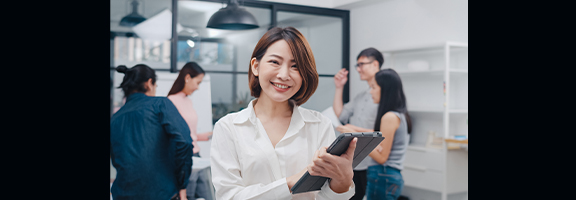 A smiling woman carrying a tablet