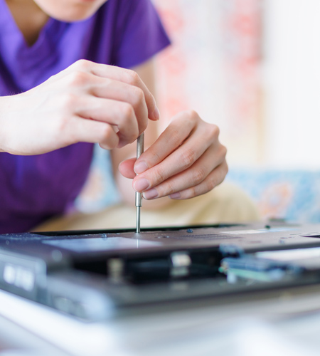 Person opening a laptop with a screwdriver