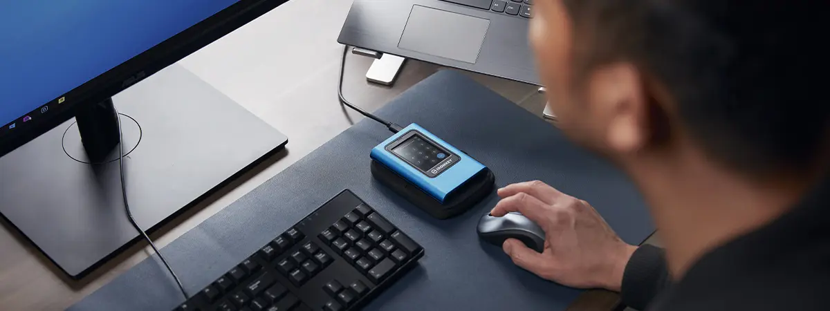 Vue par-dessus l&rsquo;&eacute;paule d&rsquo;un homme travaillant &agrave; son bureau, avec l&rsquo;IKVP80ES branch&eacute; &agrave; son ordinateur portable