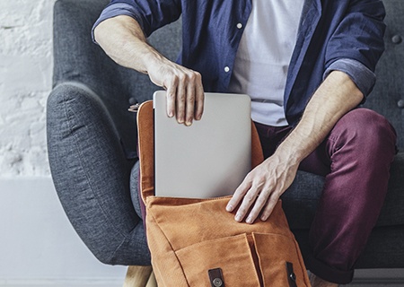 A person placing a laptop inside a backpack