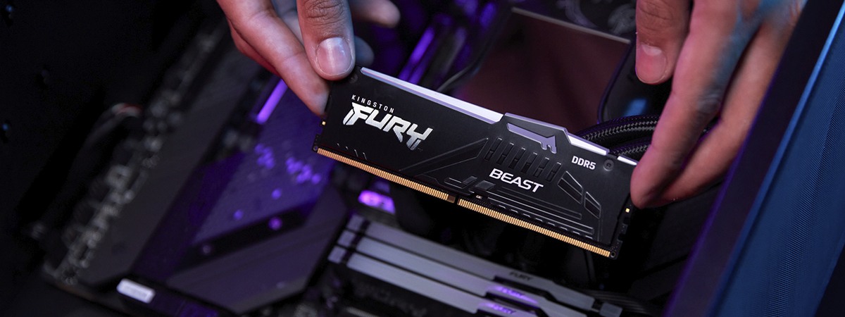 Крупный план двух рук, устанавливающих модуль Kingston FURY Beast DDR5 RGB в материнскую плату, на которой уже установлены 3 модуля