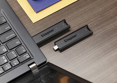 Dua drive USB-C DataTraveler Max, yang satu terpasang ke laptop dan yang lain di dekatnya dalam keadaan bebas