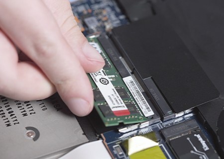 A hand installing a Kingston memory into a laptop PC