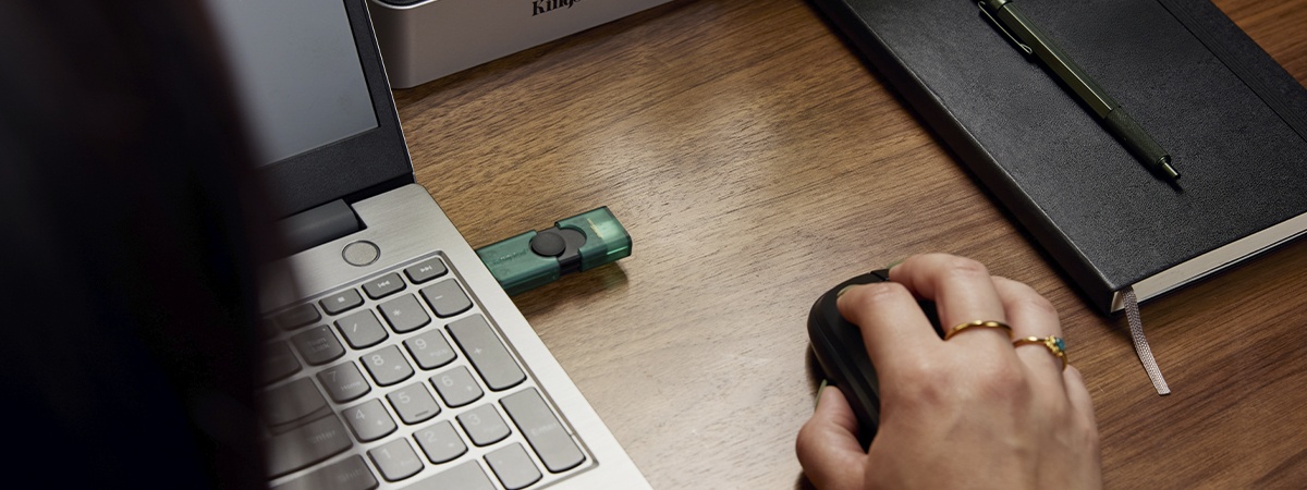 Vista dal retro di un drive USB DT Duo collegato a un laptop con una mano che usa un mouse l&igrave; accanto