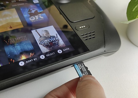 한 손으로 Canvas Go! Plus microSD를 Steam Deck microSD 슬롯에 끼워 설치하는 모습