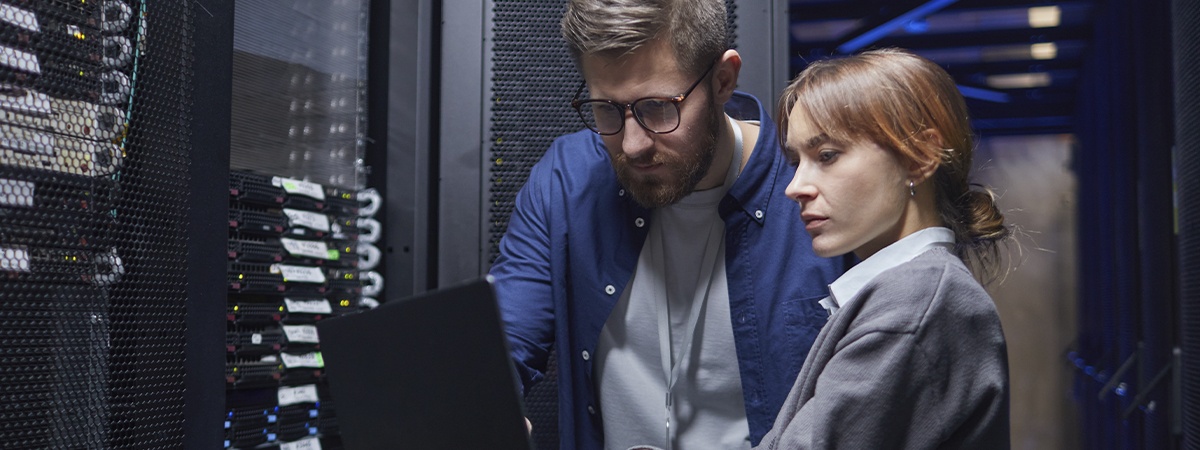 Two IT professionals are examining server connections in a data center