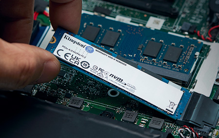 a hand inserts an M.2 NVMe SSD into a motherboard