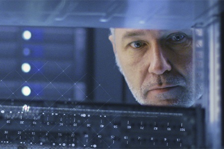 Man looking through the space in a server rack