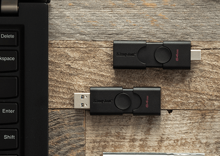 Bir masa üzerinde yer alan bir dizüstü bilgisayar ve USB-A ve USB-C konektörlü Kingston DataTraveler Duo flash bellek