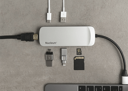 a close-up image of the Nucleum hub plugged in a laptop on a desk with USBs and cards for different ports