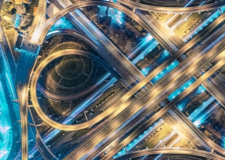 Vista dall’alto di una strada trafficata e ponti con immagini raffiguranti scie di luce blu che sfrecciano ad alta velocità