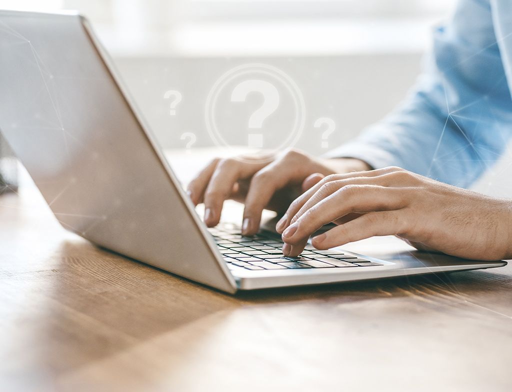 一只手在笔记本电脑键盘上打字，顶部是问号和网络线条