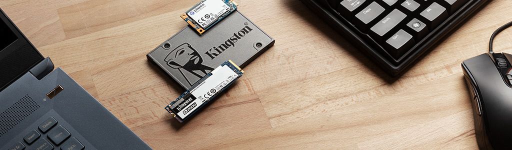 Desktop PC and laptop sitting on a table with Kingston SSDs sitting nearby