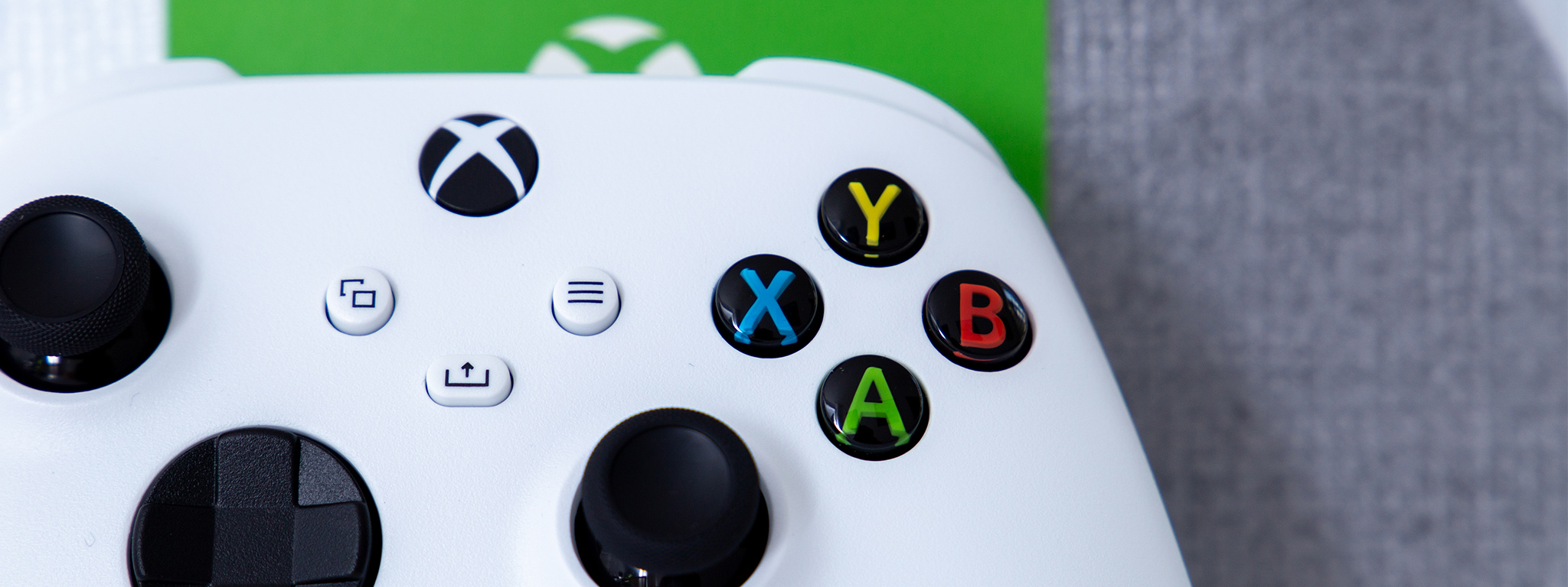 Gros plan sur une manette Xbox Series S blanche sur fond blanc et vert.