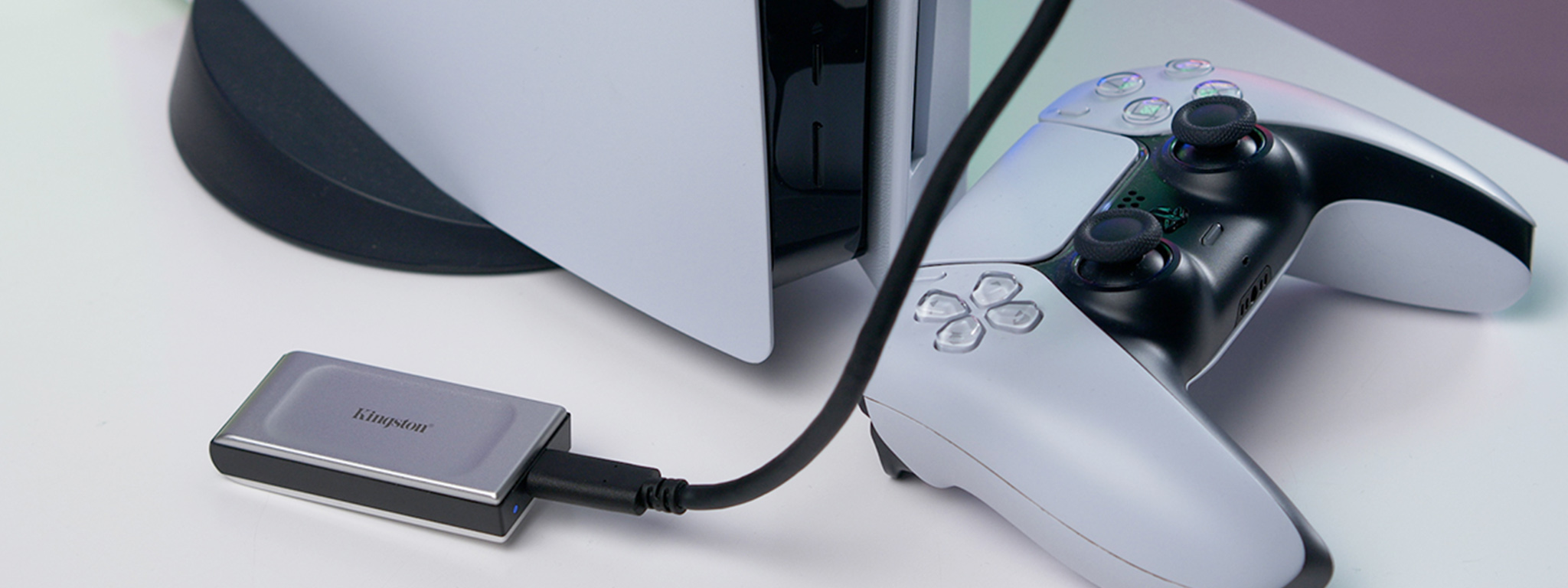 Um PlayStation5 e um controle com um SSD externo Kingston XS2000 ligado por USB.