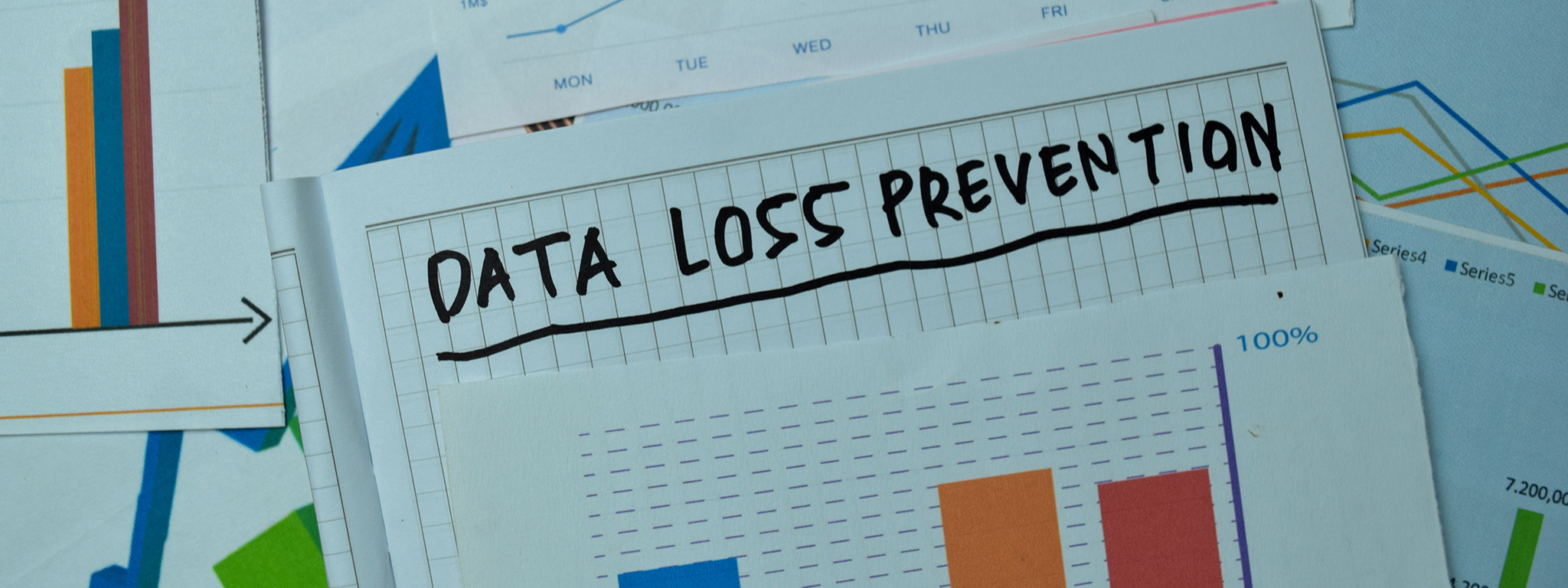 Слова &quot;Data Loss Prevention&quot; (Предотвращение потери данных), написанные на заметках с графиками и диаграммами на офисном столе.