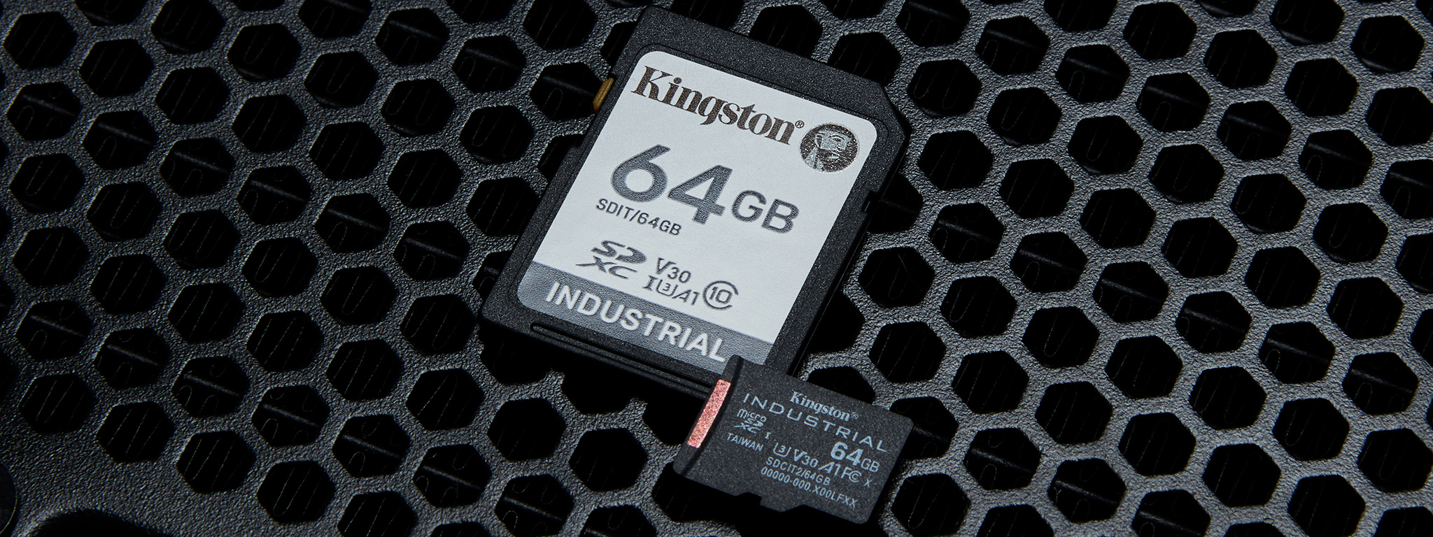 A pair of Kingston 64GB Industrial microSD cards siting on a distressed metal surface