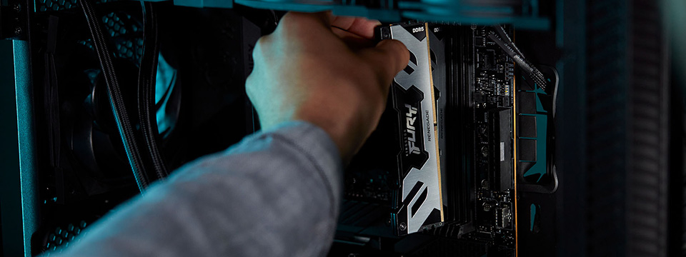 Seseorang memasukkan modul memori Kingston FURY Renegade DDR5 ke casing komputer berwarna hitam.