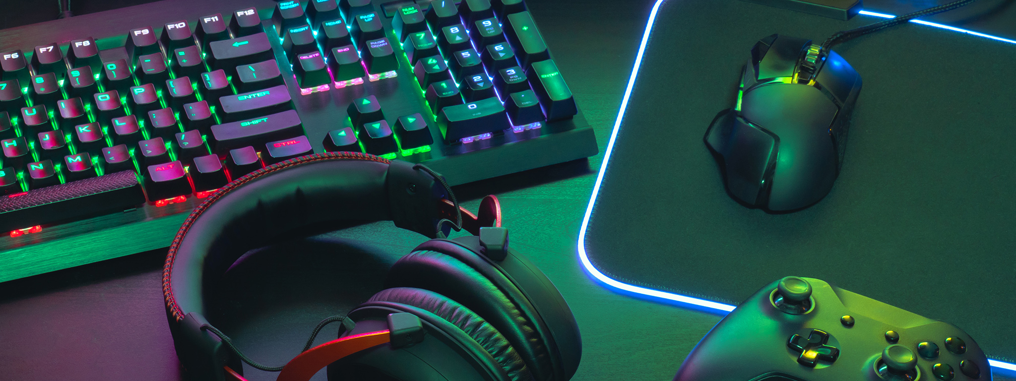 A gamer’s desk featuring an RGB keyboard, gamer headset, gaming mouse and RGB mouse pad, and a wireless Xbox controller