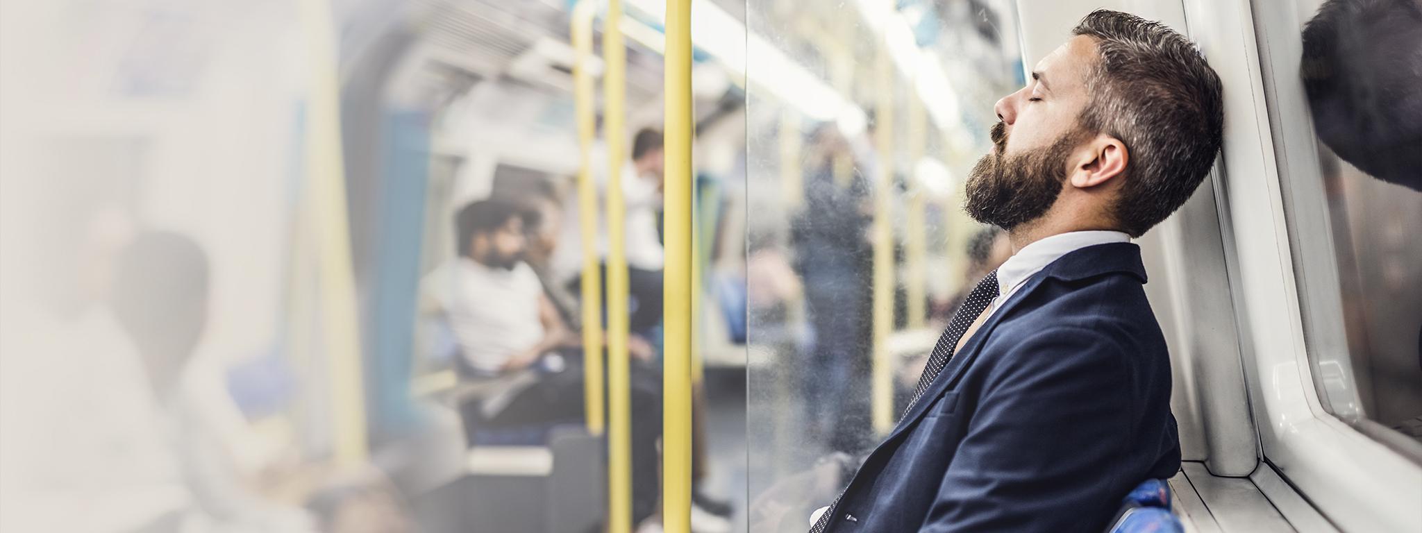 Un hombre de negocios dormido viajando al trabajo en un tren del metro de Londres