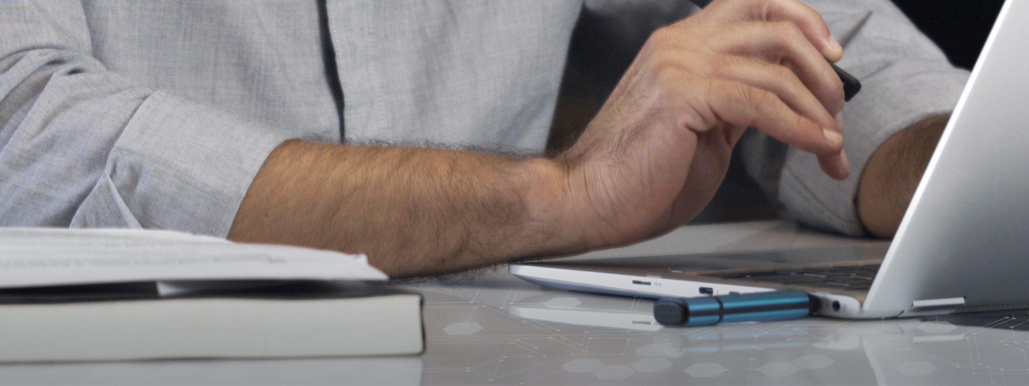 一個男人在鍵盤上打字，筆記型電腦上插入 Kingston IronKey USB 隨身碟的特寫畫面
