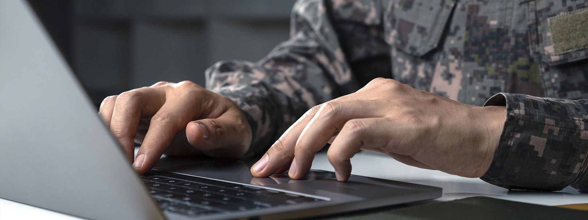 Um soldado de uniforme camuflado trabalhando em um laptop